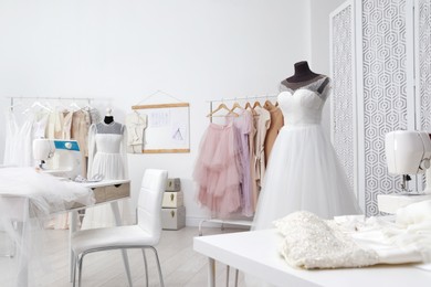 Dressmaking workshop interior with wedding dresses, female clothes and equipment