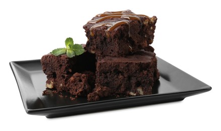 Photo of Delicious chocolate brownies with nuts, caramel sauce and fresh mint on white background