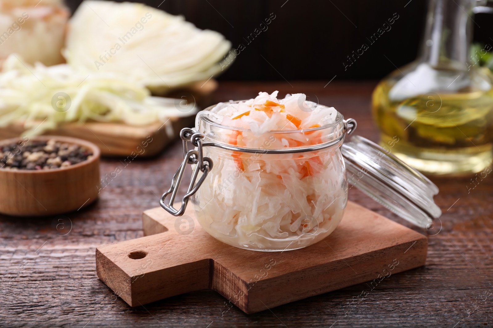 Photo of Glass jar of tasty sauerkraut on wooden table