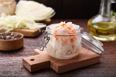 Glass jar of tasty sauerkraut on wooden table