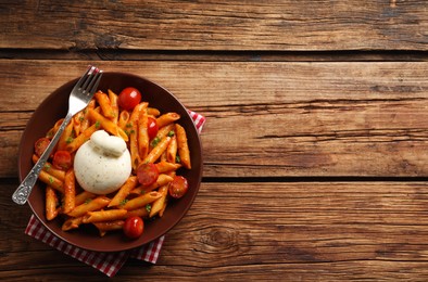 Photo of Delicious pasta with burrata cheese and tomatoes on wooden table, top view. Space for text