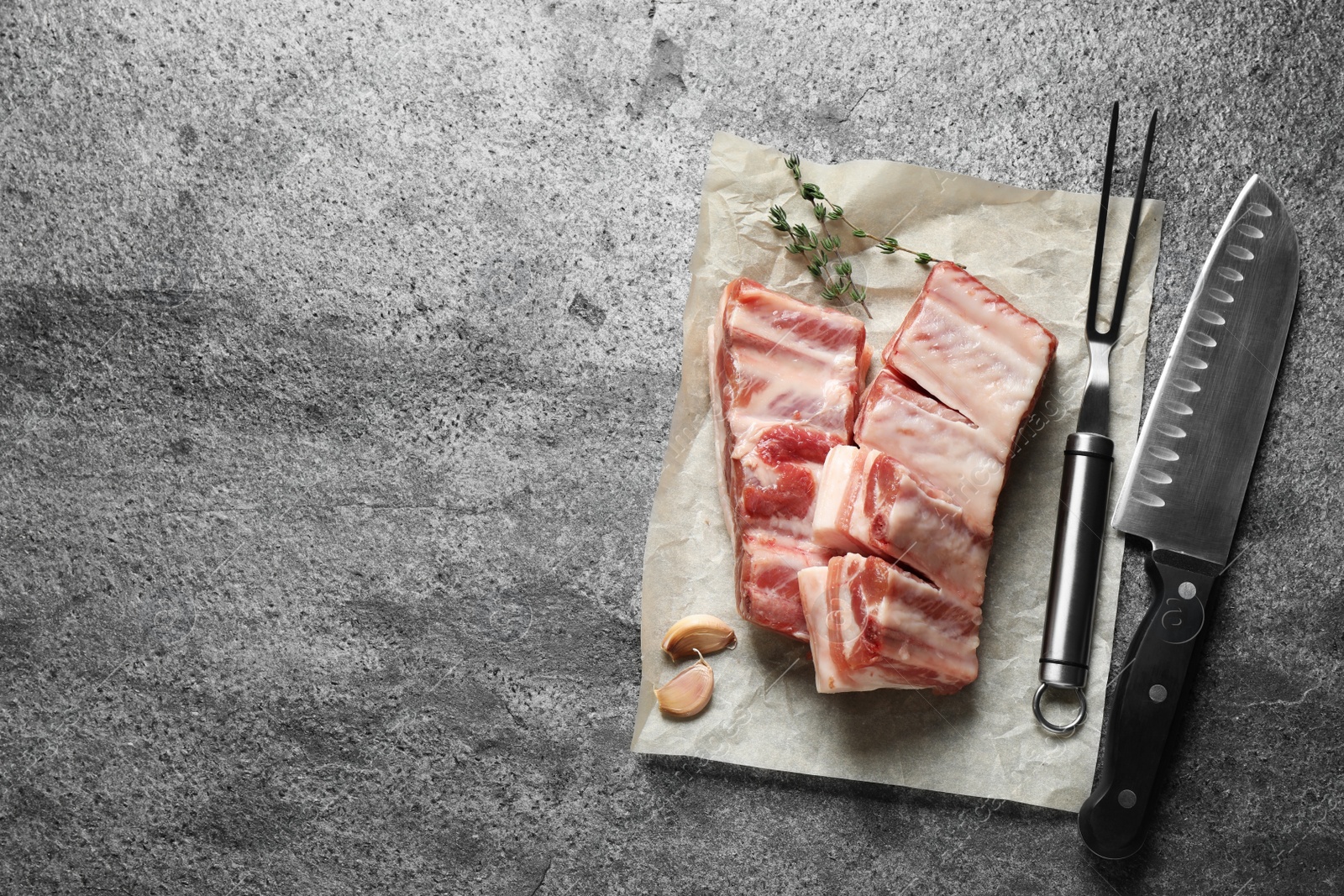 Photo of Raw ribs with thyme on grey table, flat lay. Space for text