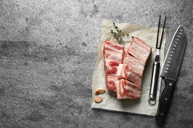 Photo of Raw ribs with thyme on grey table, flat lay. Space for text