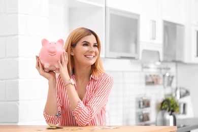 Photo of Woman with piggy bank and money at home. Space for text