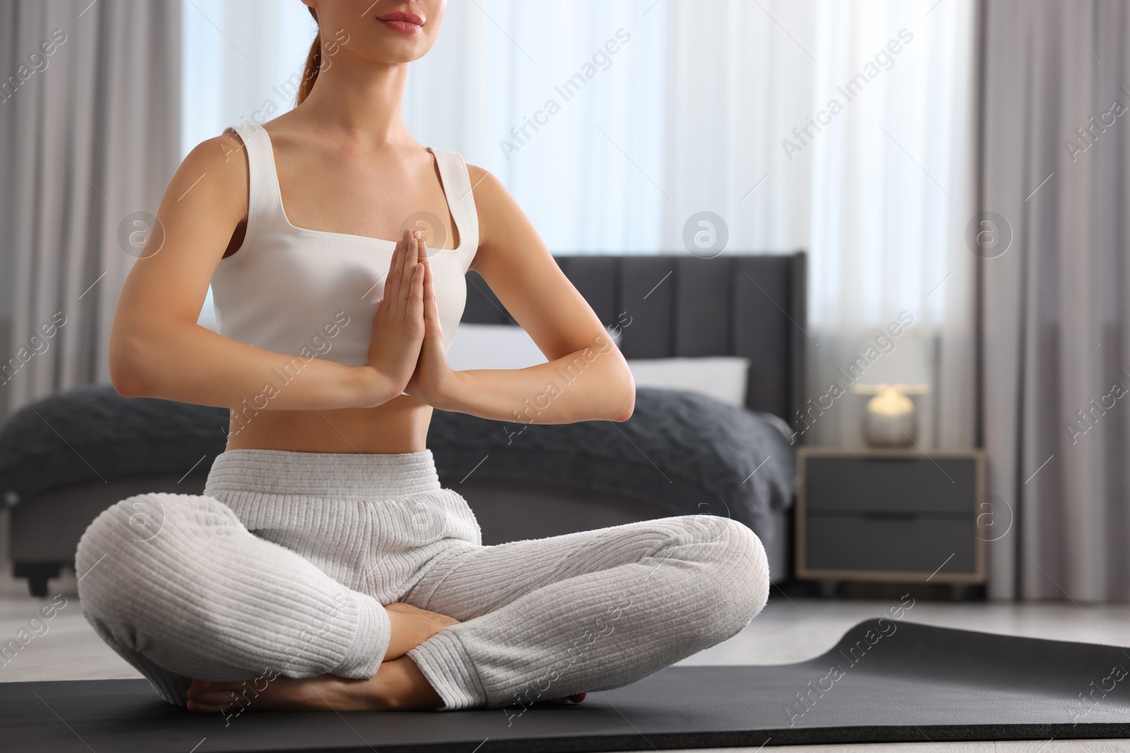Photo of Woman practicing Padmasana on yoga mat at home, closeup and space for text. Lotus pose