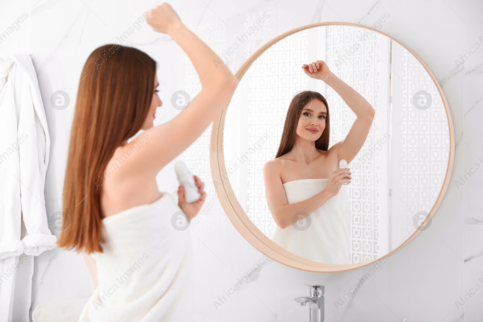 Photo of Beautiful young woman applying deodorant after shower in bathroom