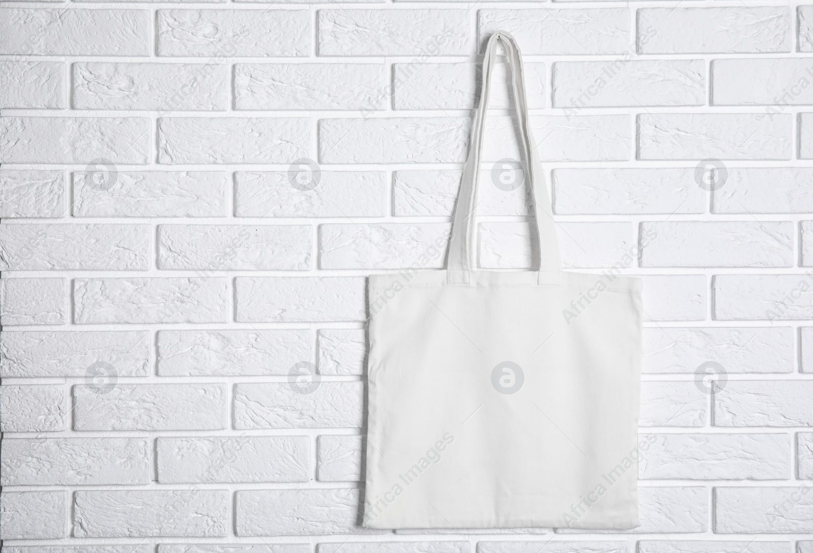 Photo of Tote bag hanging on brick wall. Mock up for design