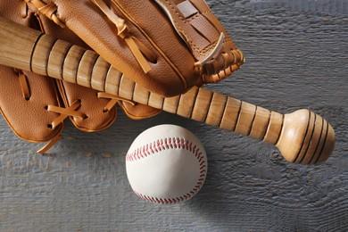 Baseball glove, bat and ball on grey wooden table, closeup