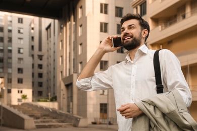 Photo of Handsome man talking on phone in modern city