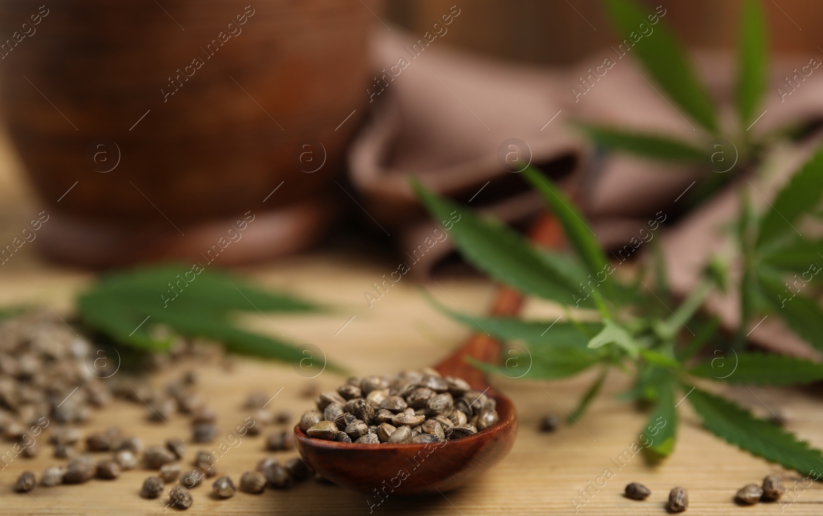 Photo of Organic hemp seeds and leaves on wooden table, closeup. Space for text