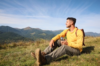 Photo of Tourist with thermos and backpack enjoying beautiful mountain landscape