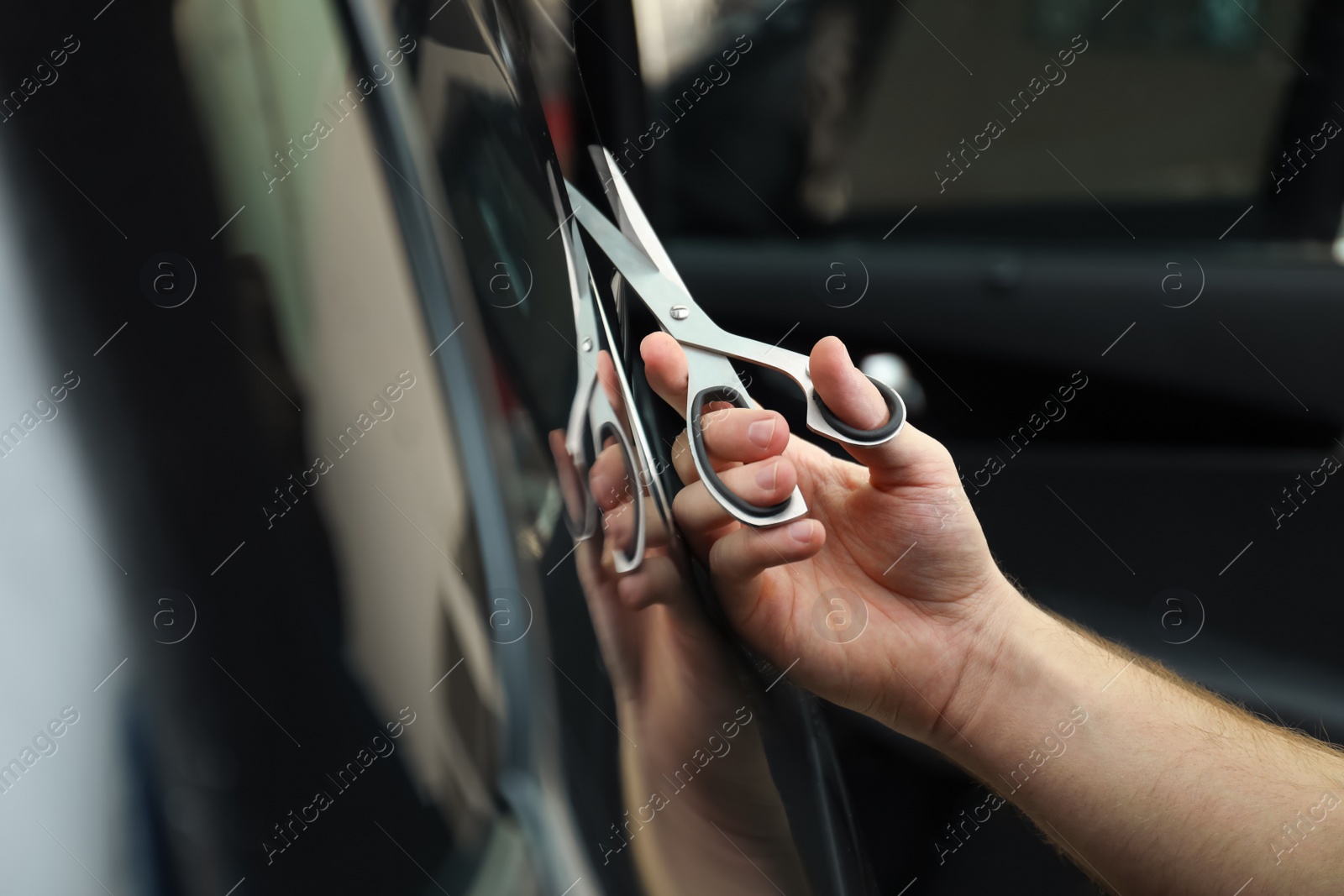 Photo of Worker tinting car window with foil in workshop, closeup