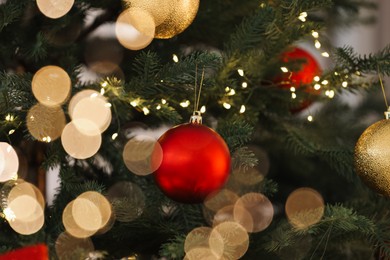 Photo of Christmas tree decorated with festive balls and lights, closeup