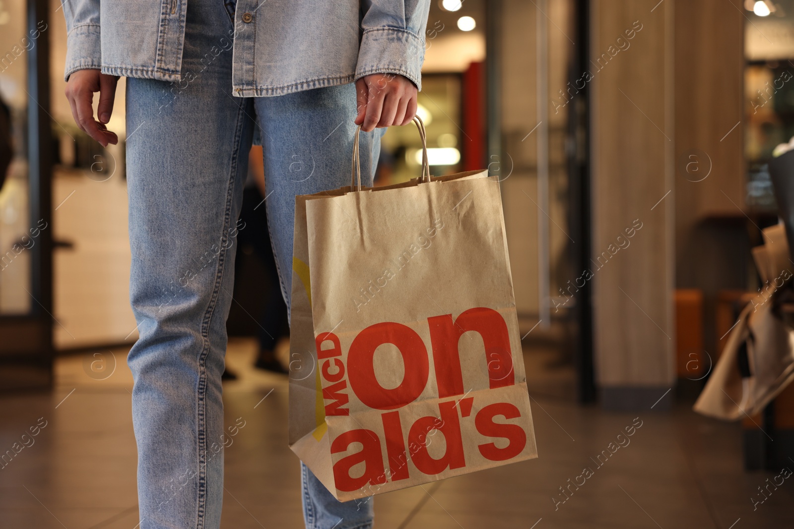 Photo of Lviv, Ukraine - September 26, 2023: Woman with McDonald's paper bag in cafe, closeup. Space for text