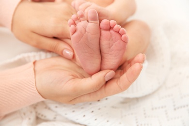 Photo of Mother holding little baby feet in hands