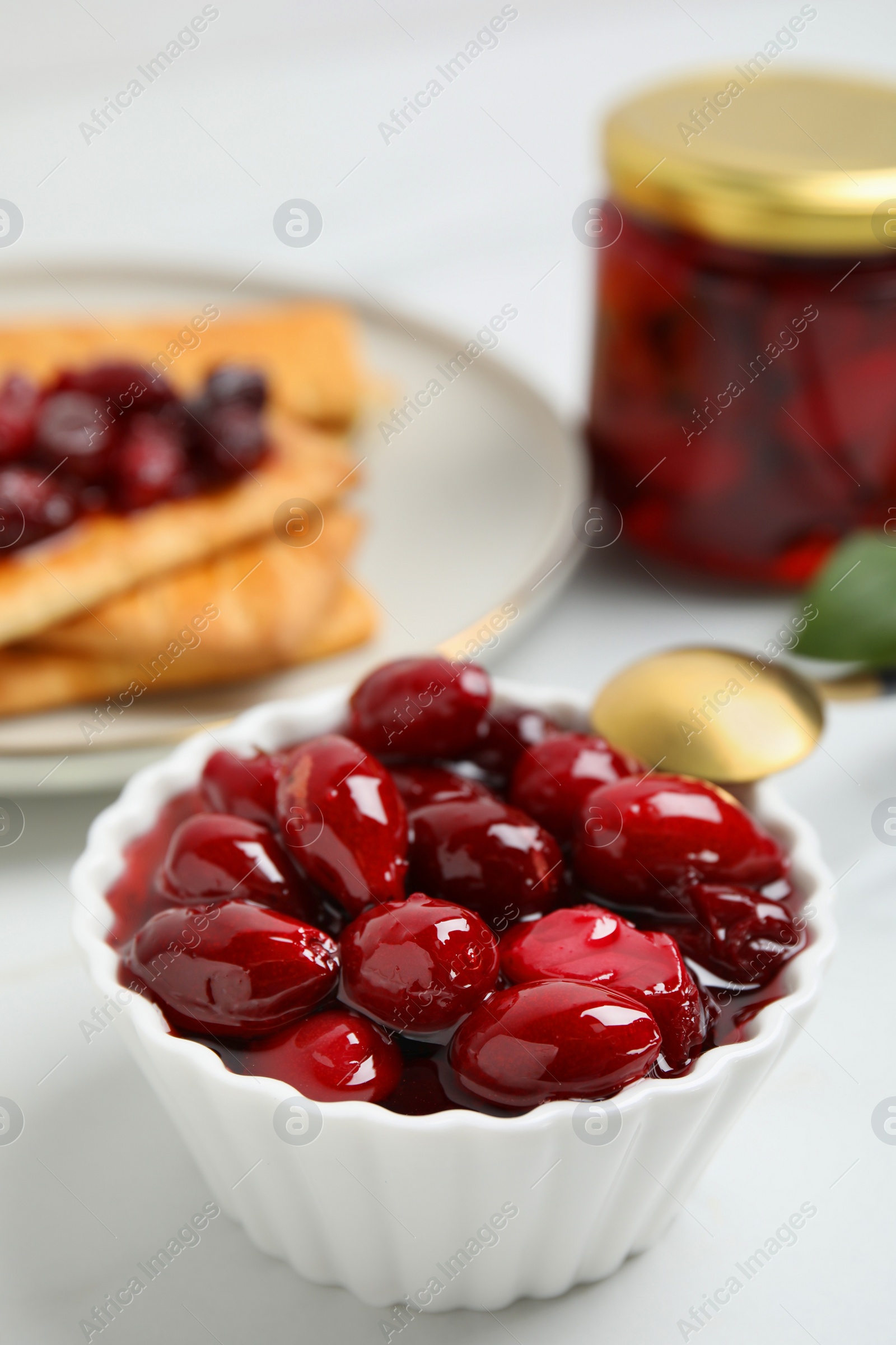 Photo of Delicious dogwood jam with berries in bowl on white table, space for text