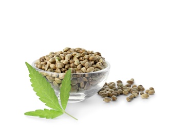 Photo of Bowl of hemp seeds with green leaf on white background