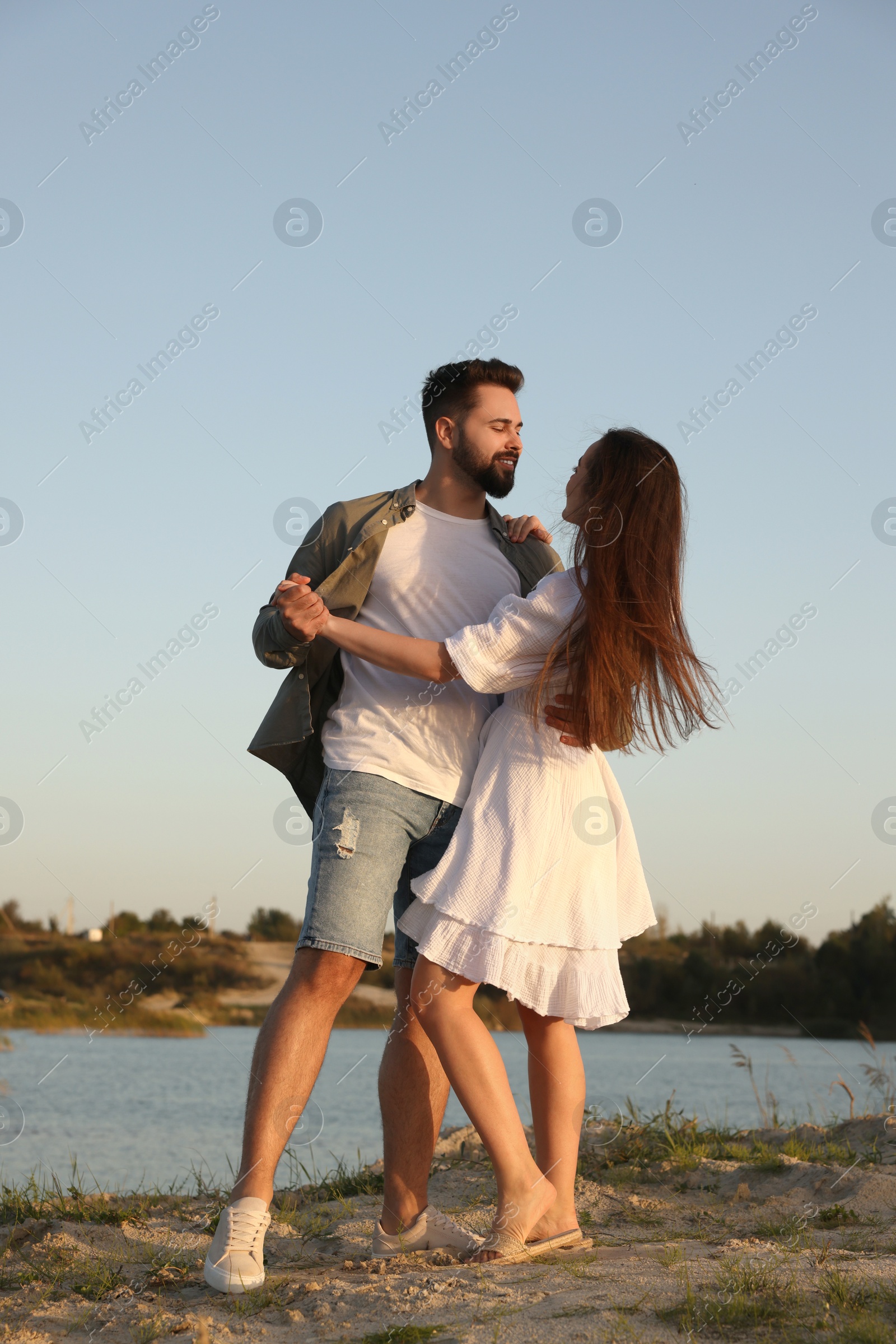 Photo of Beautiful couple dancing near river at sunset