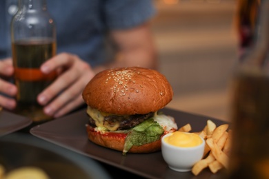Photo of Tasty burger with French fries served on table in cafe