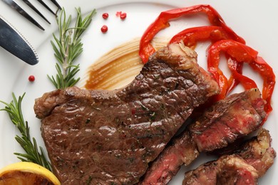 Photo of Delicious grilled beef steak with pepper and spices served on plate, top view