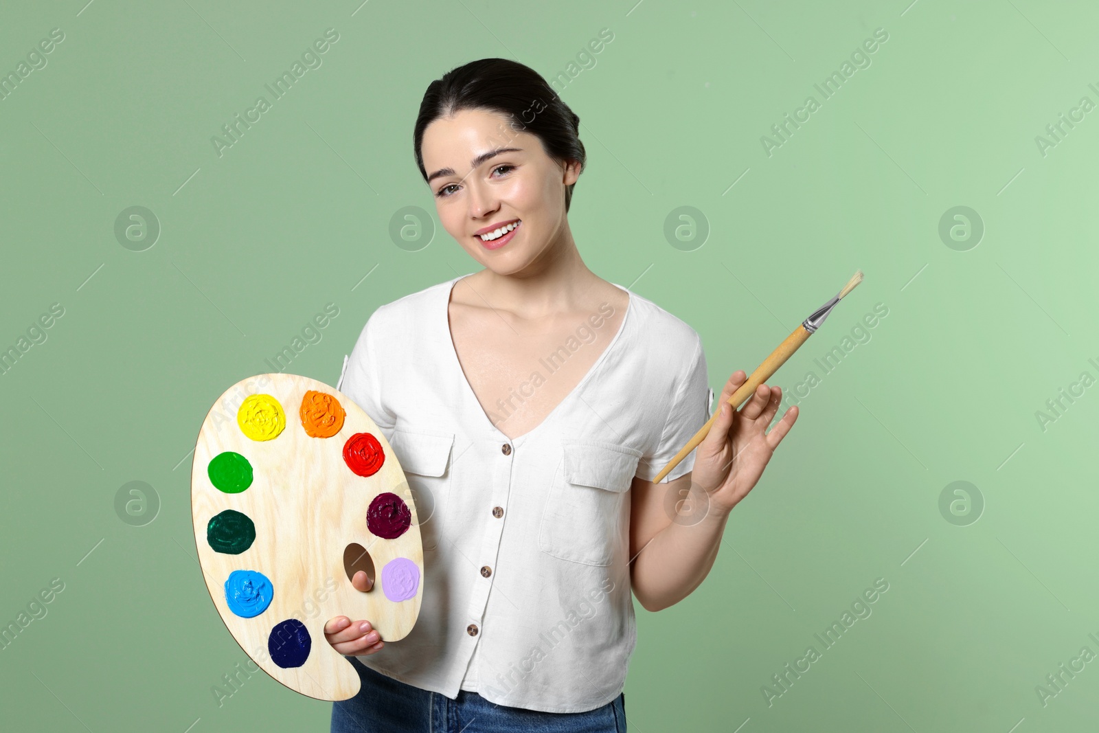 Photo of Woman with painting tools on pale green background. Young artist