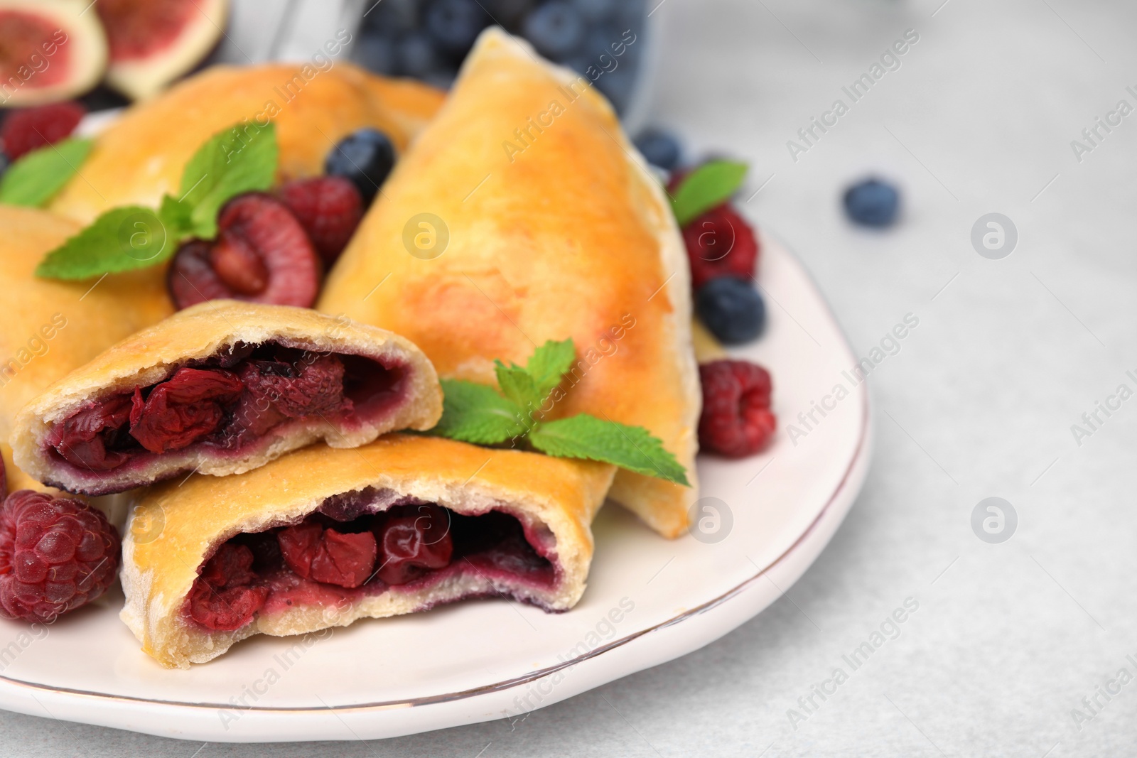 Photo of Plate of delicious samosas, berries and mint leaves on white table, closeup. Space for text