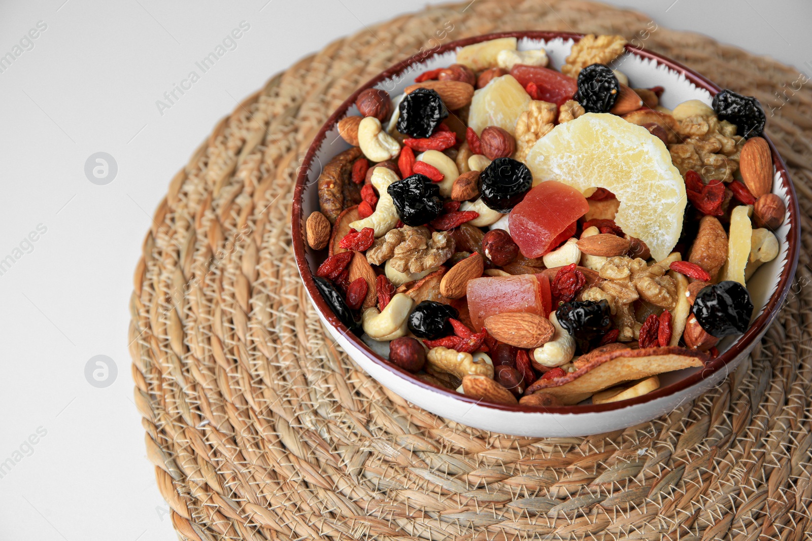 Photo of Bowl with mixed dried fruits and nuts on white table, space for text