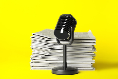 Newspapers and vintage microphone on yellow background. Journalist's work