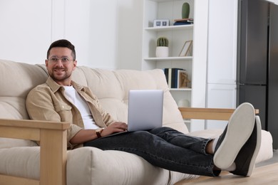 Happy man working with laptop on sofa at home