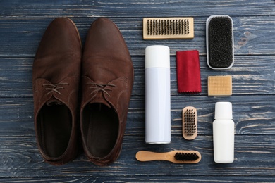 Stylish footwear with shoe care accessories on blue wooden table, flat lay