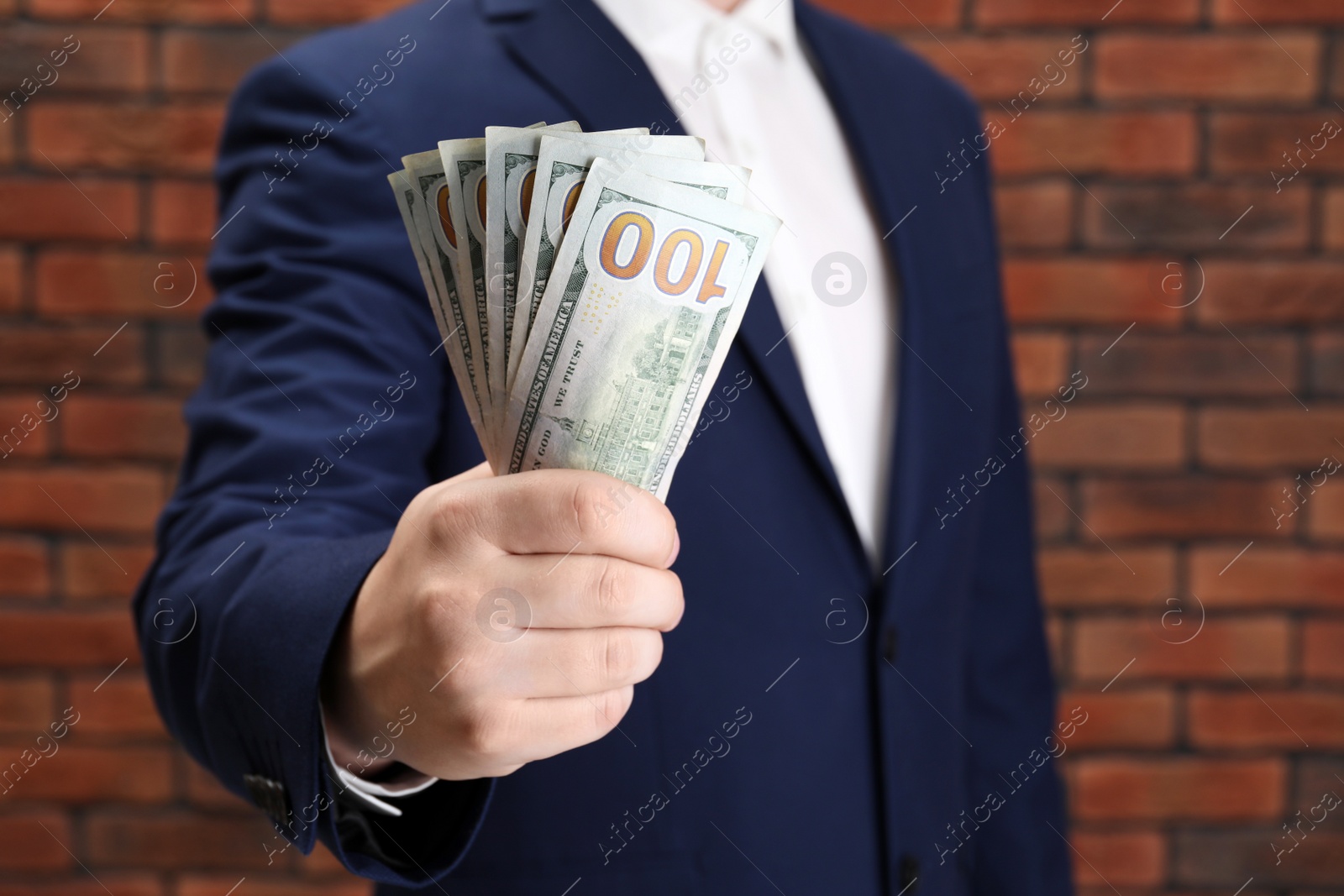 Photo of Man holding money near red brick wall, closeup. Currency exchange