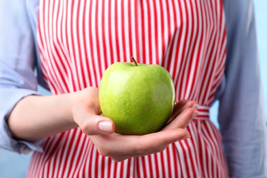 Woman holding ripe green apple, closeup view