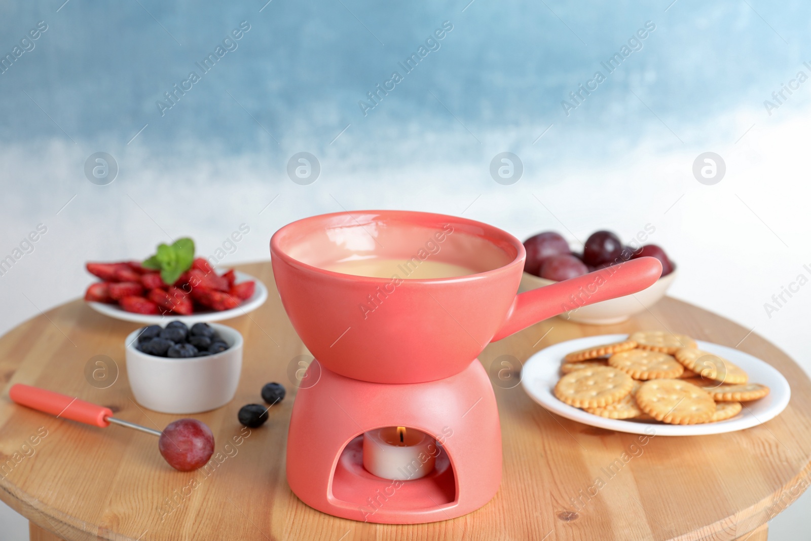 Photo of Ceramic pot with white chocolate fondue on table