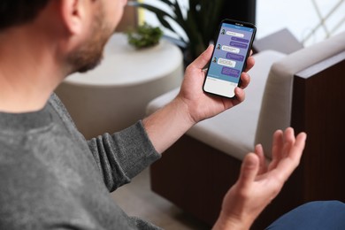 Image of Man texting via mobile phone indoors, closeup. Device screen with messages