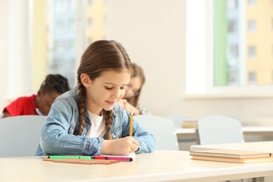 Cute little girl studying in classroom at school. Space for text