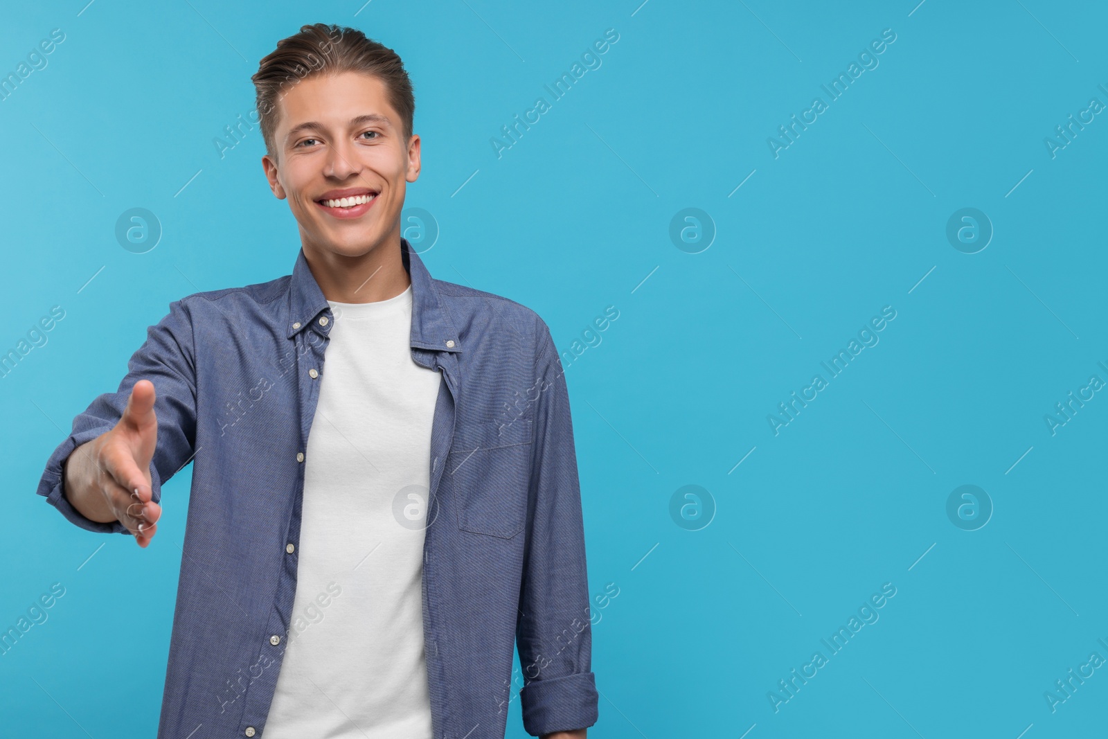 Photo of Happy man welcoming and offering handshake on light blue background. Space for text