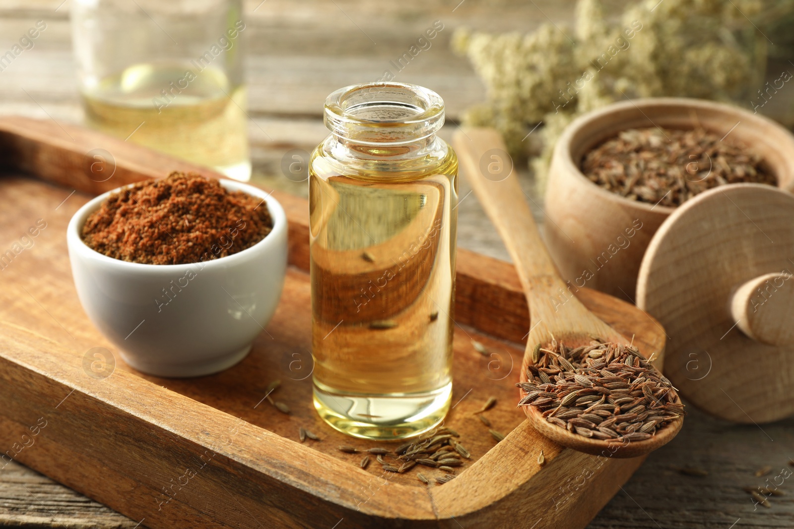 Photo of Caraway (Persian cumin) seeds, powder and essential oil on table, closeup