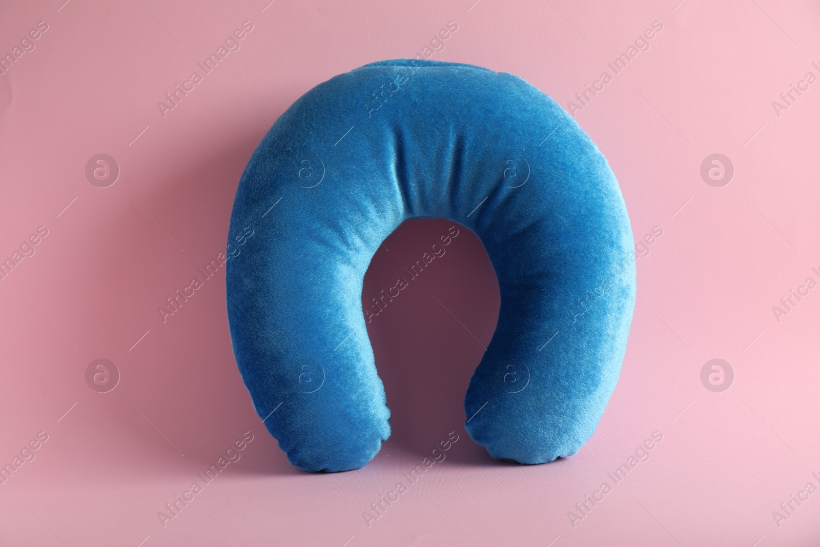 Photo of Light blue travel pillow on pink background