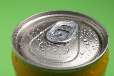 Photo of Energy drink in wet can on green background, closeup