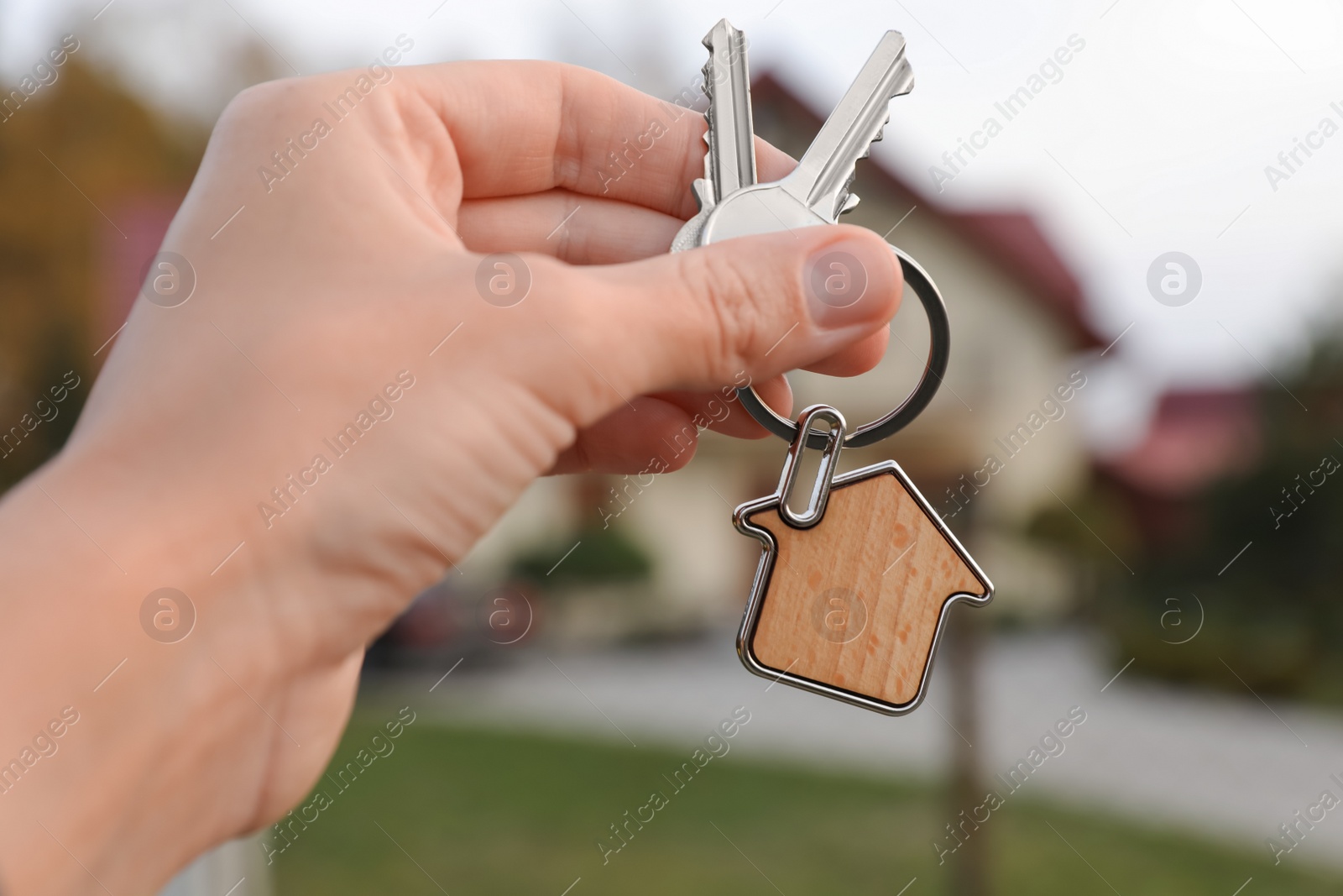 Photo of Woman holding house keys outdoors, closeup. Real estate agent