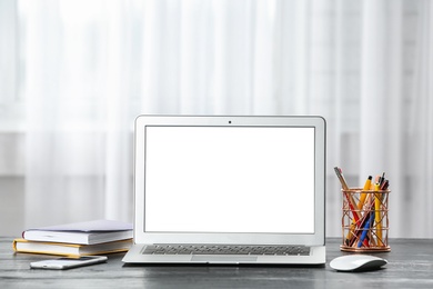 Photo of Laptop on desk near window in home office. Comfortable workplace