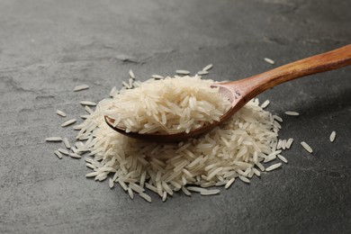 Photo of Raw basmati rice and wooden spoon on black table