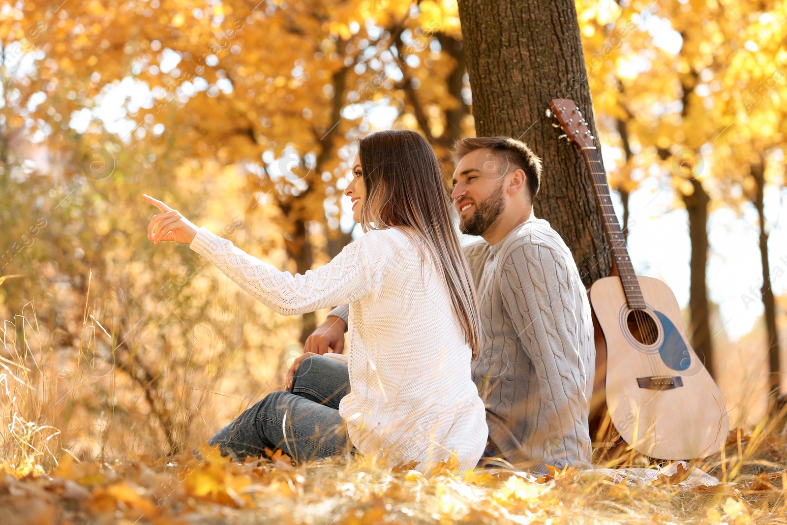 Photo of Young couple with guitar in autumn park