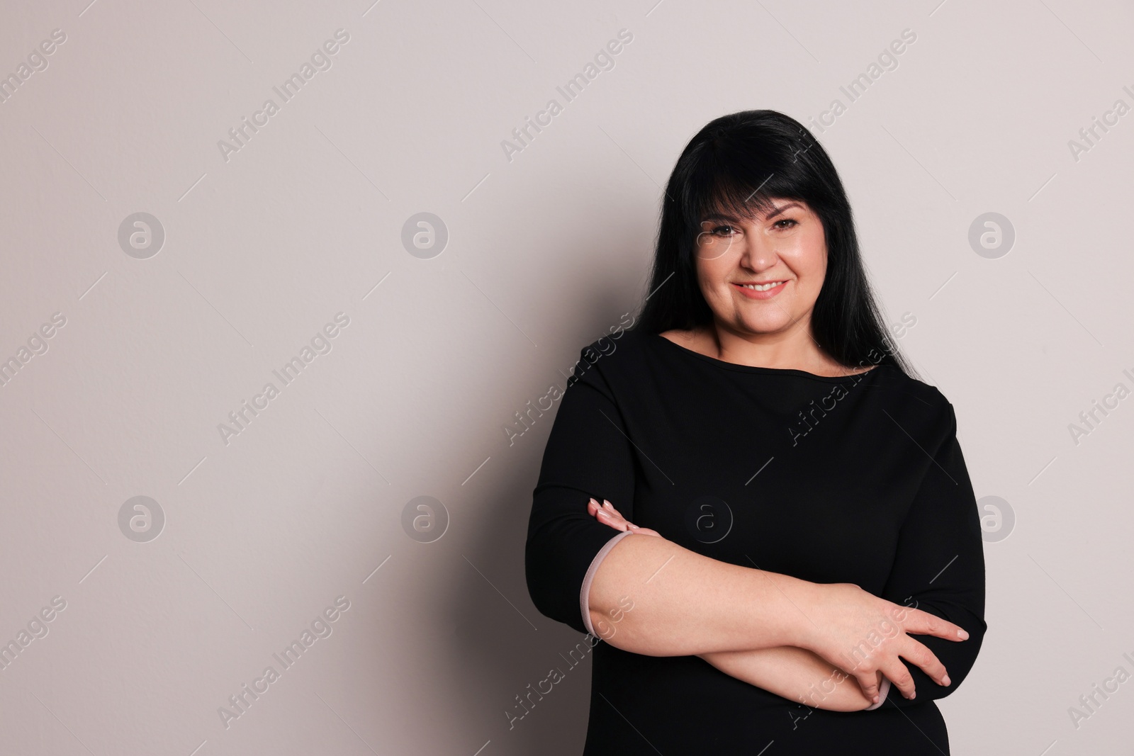 Photo of Beautiful overweight mature woman with charming smile on light grey background. Space for text