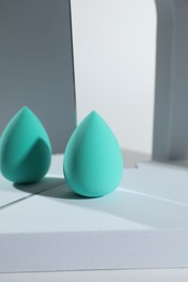 Stylish presentation of turquoise makeup sponge on white background