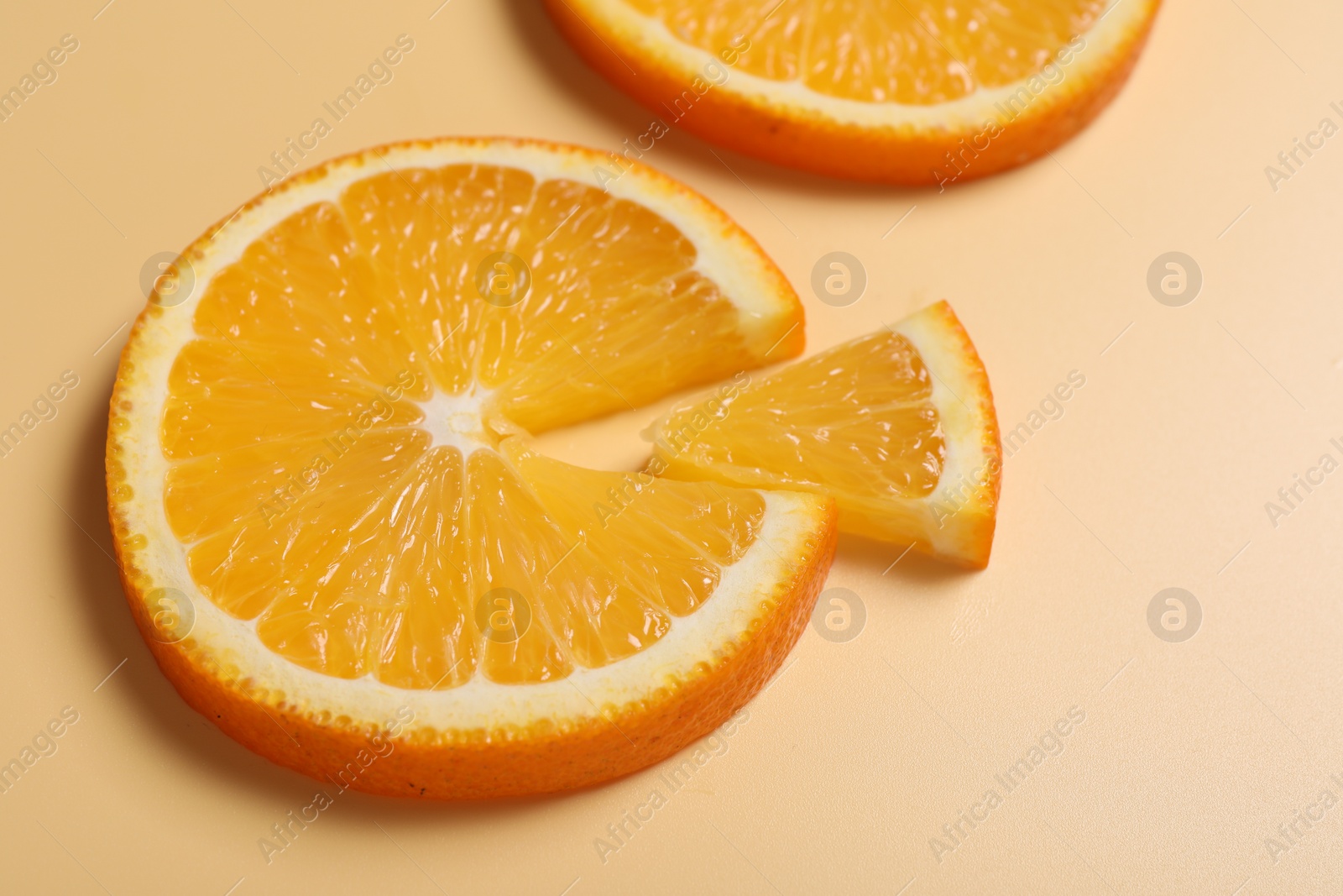 Photo of Slices of juicy orange on beige background, closeup