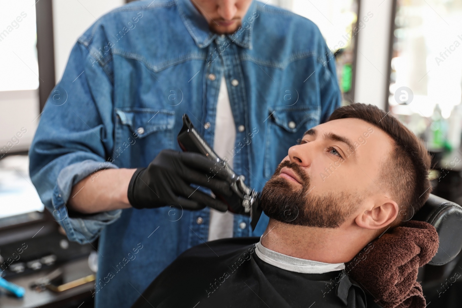 Photo of Professional barber working with client in hairdressing salon. Hipster fashion