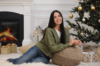 Photo of Portrait of smiling woman surrounded by gift boxes in room decorated for Christmas