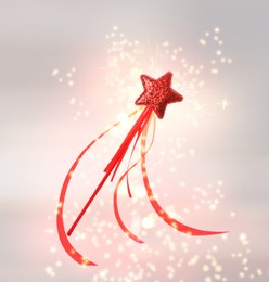 Image of Beautiful red wand and shiny magical dust on light background