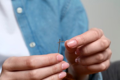 Woman inserting thread through eye of needle, closeup